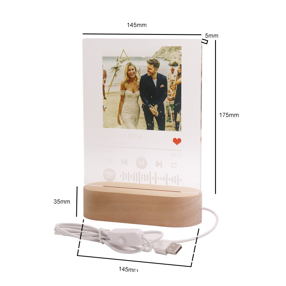 Digital photo frame with wooden base and cable, showing dimensions on a white background.