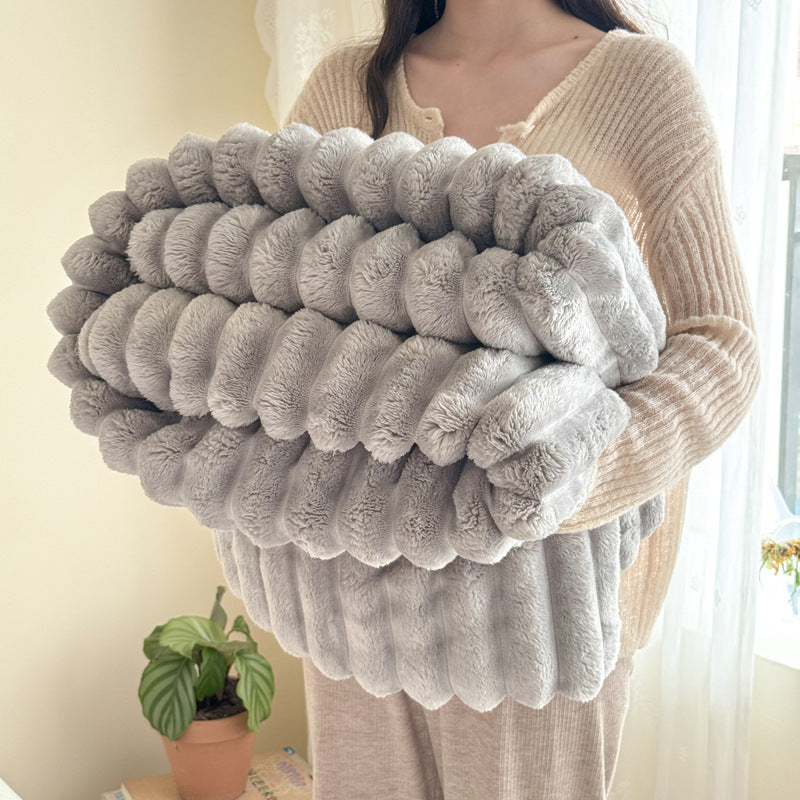 Person holding a large, fluffy gray pillow in a home setting.