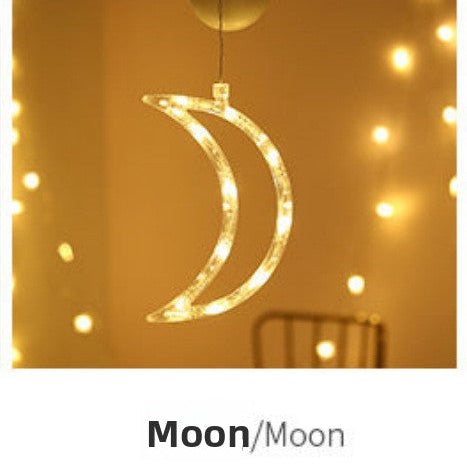 Decorative moon-shaped light hanging against a warm-toned background with string lights.