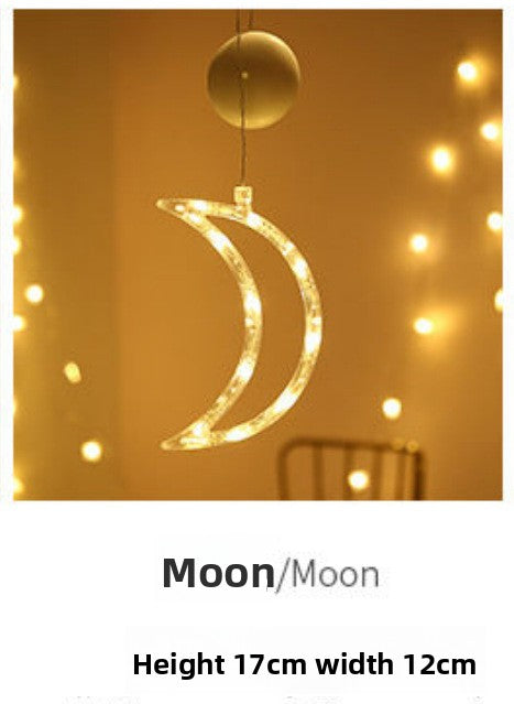 Decorative moon-shaped light hanging against a warm-toned background with string lights.