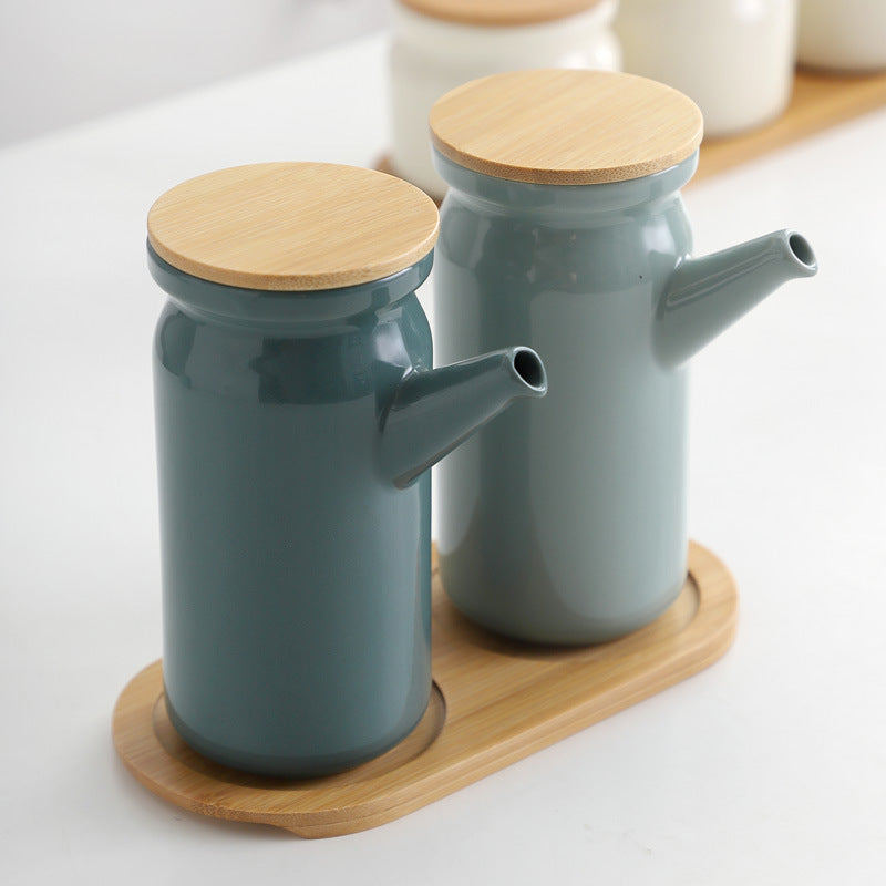 Two blue ceramic oil dispensers with wooden lids on a wooden stand.