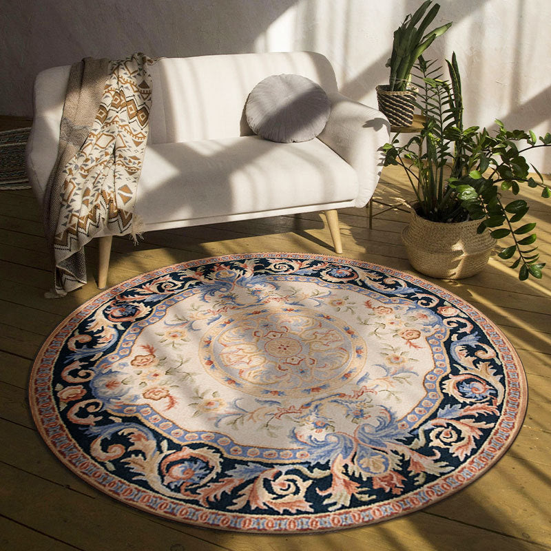 Decorative round rug with intricate patterns in a room with a white sofa and plants.