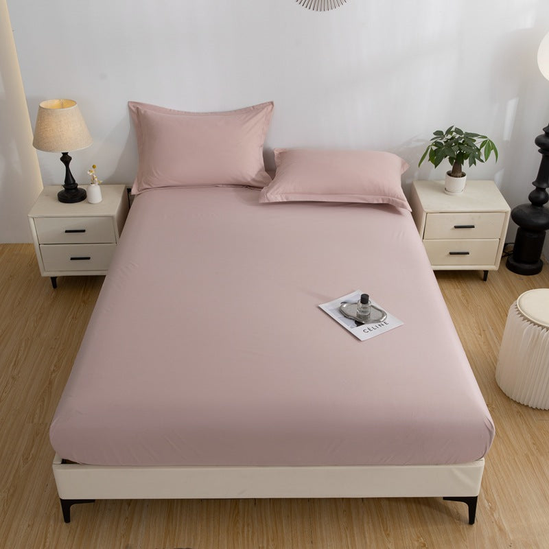 Bed with pink fitted sheet and pillows in a bedroom setting.