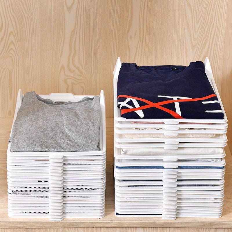 Stacks of folded shirts on white trays against a wooden background