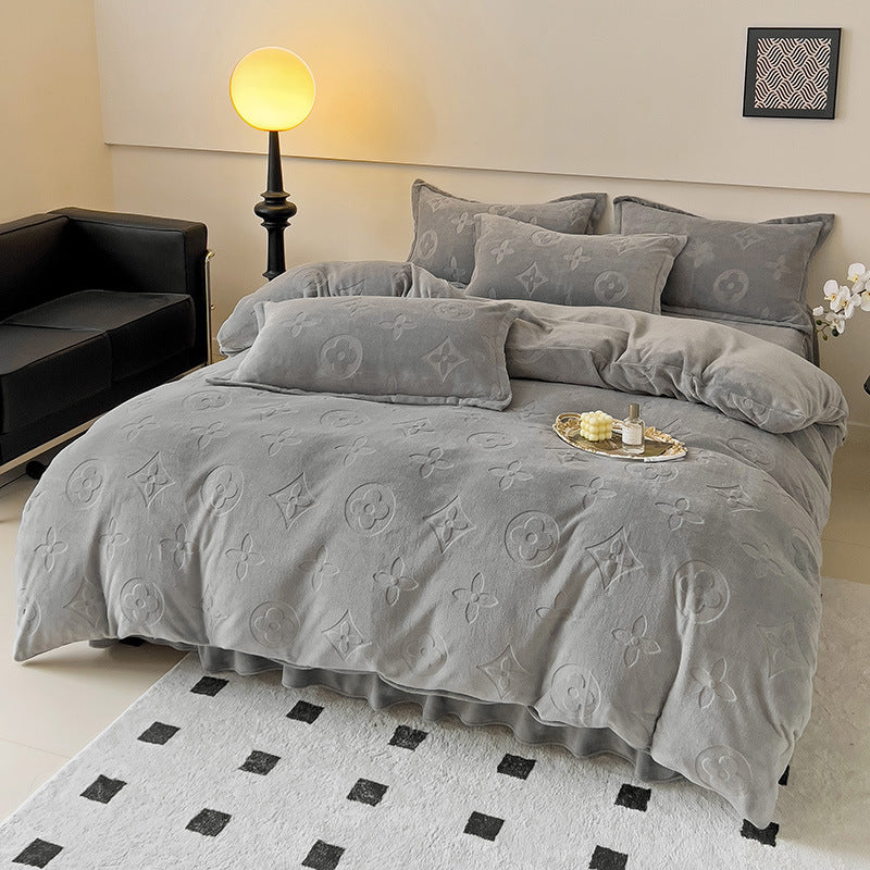 Gray textured comforter set on a bed in a bedroom with a lamp and sofa.