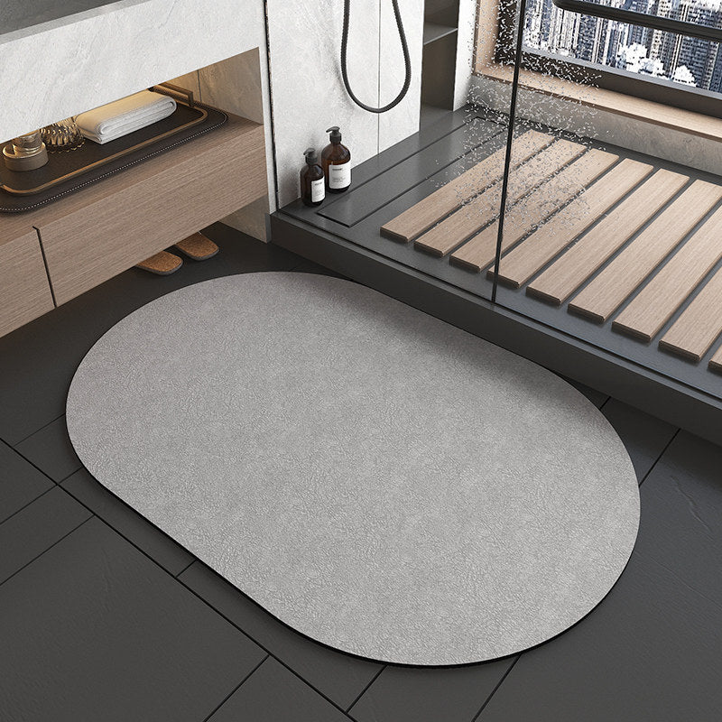 Gray bath mat on a black tiled floor with a shower area in the background.