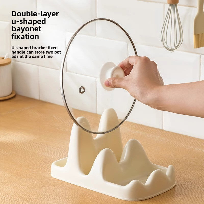 White pot lid organizer with a hand placing a pot lid on it, set against a kitchen background.