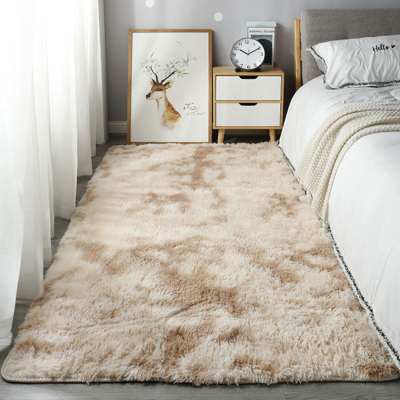 Beige shaggy rug in a bedroom setting with a bed, nightstand, and wall art.