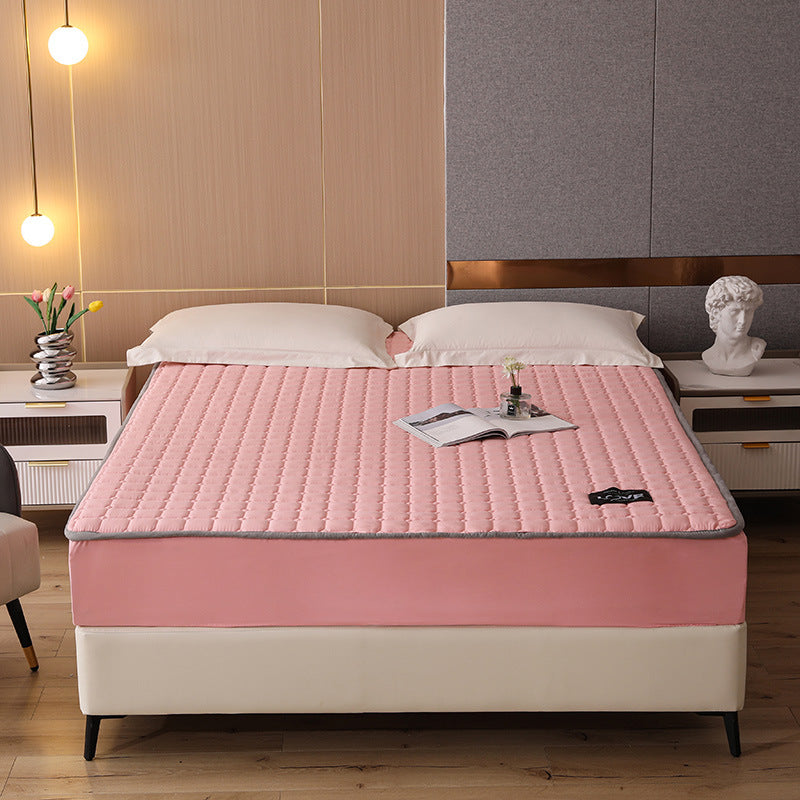Pink mattress cover on a bed in a bedroom setting with decor elements.