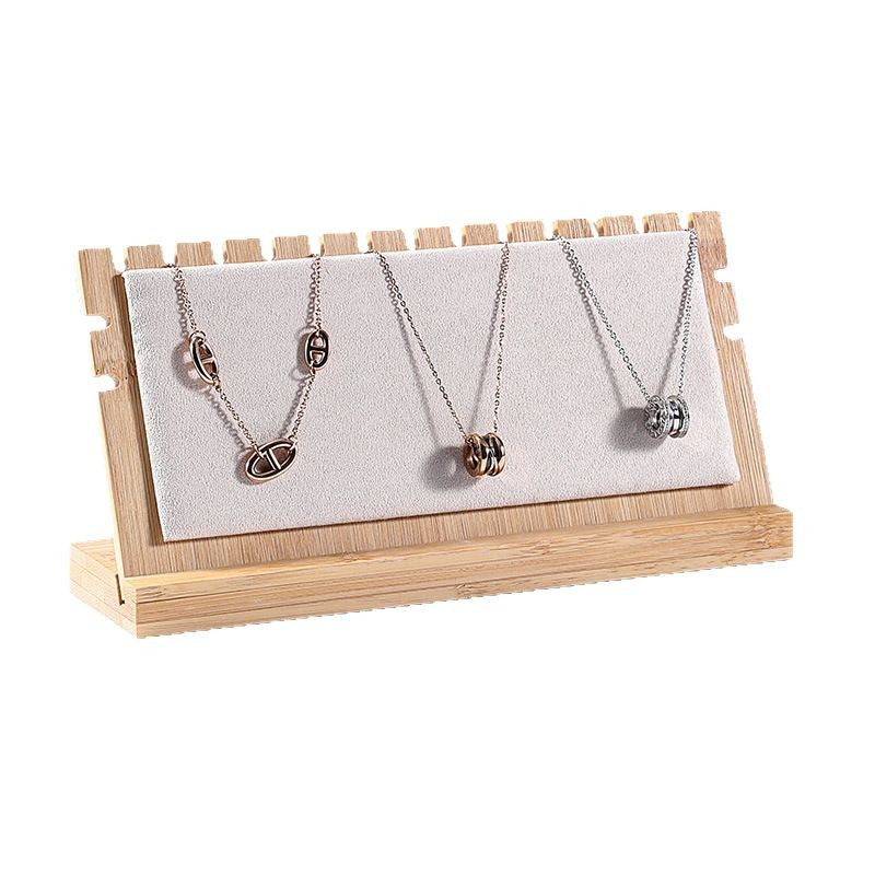 Three necklaces on a wooden stand with a white background