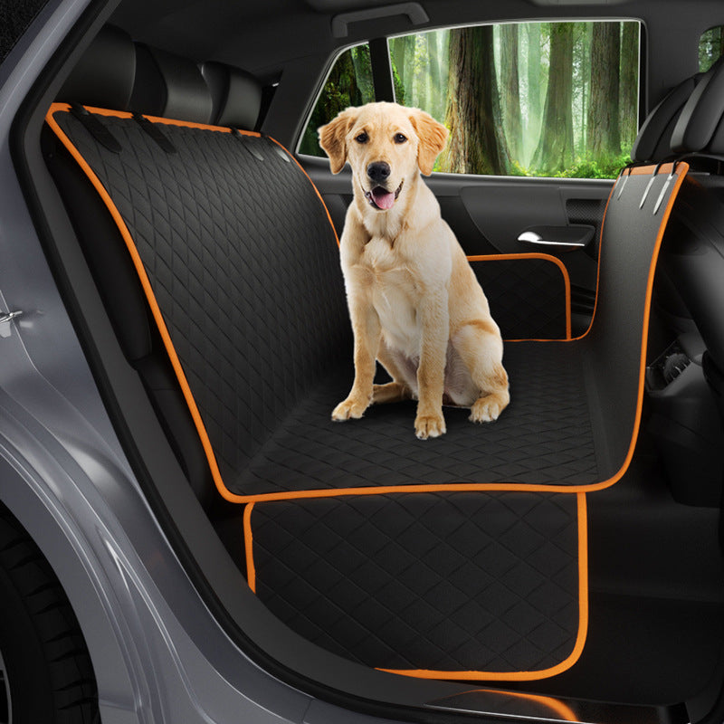 Dog sitting on a black car seat cover with orange trim in a vehicle.