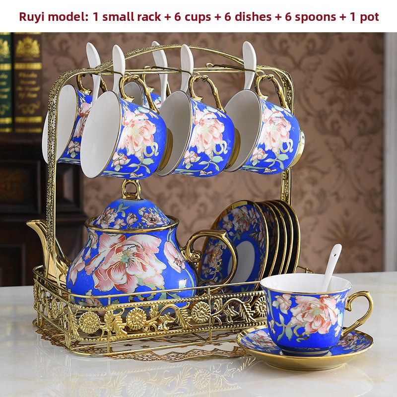 Ceramic tea set with floral design on a decorative stand against a patterned wall.