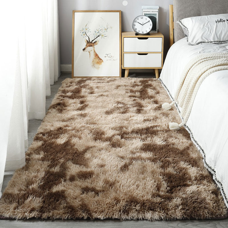 Fluffy brown rug on a wooden floor with a bed and nightstand in the background.