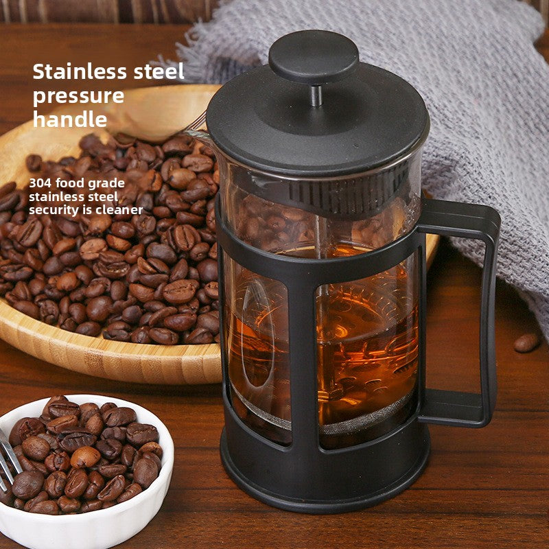 French press with coffee beans and brewed coffee on a wooden surface