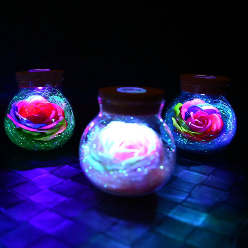 Three glowing jars with rose designs on a dark surface