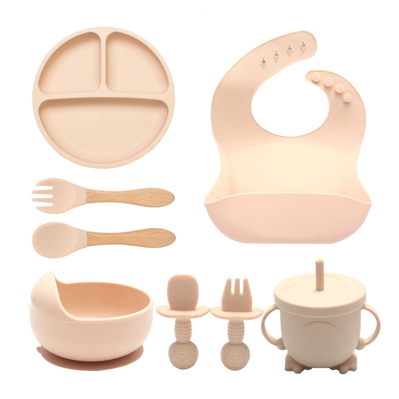 Set of baby feeding utensils including a plate, bowl, spoon, fork, and cup on a white background.