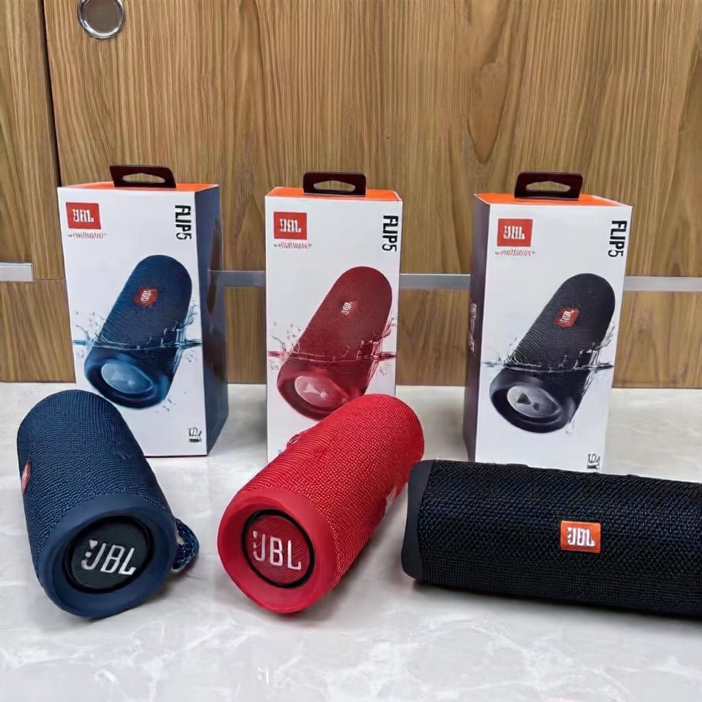 Three JBL Flip 5 portable speakers with their packaging on a white surface.