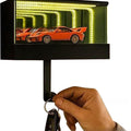 Keychain with a small LED display showing an orange sports car, held by a hand.
