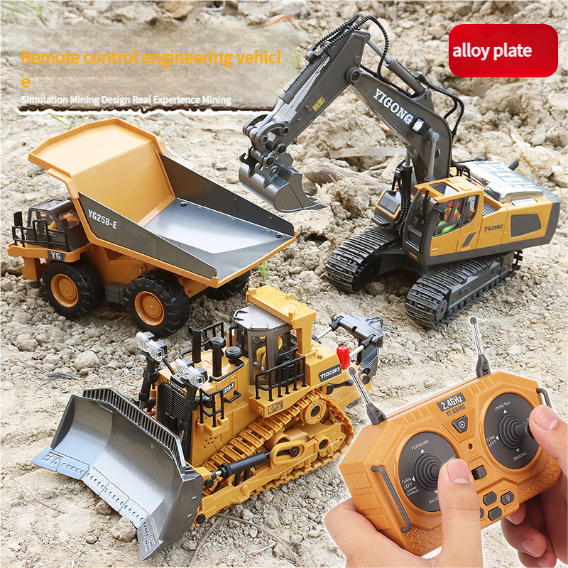 Toy construction vehicles including a dump truck, excavator, and bulldozer on a sandy surface with a remote control.