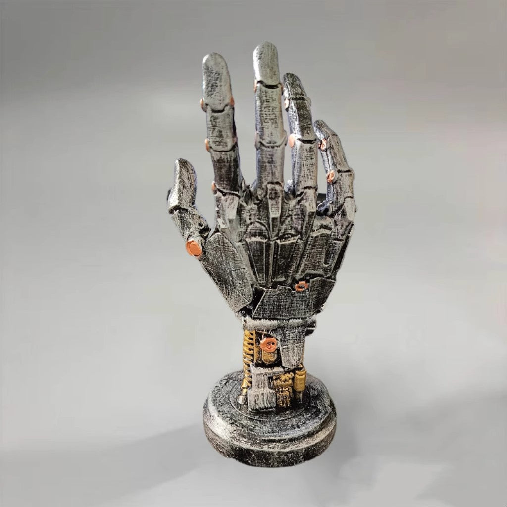 Metallic mechanical hand sculpture on a gray background
