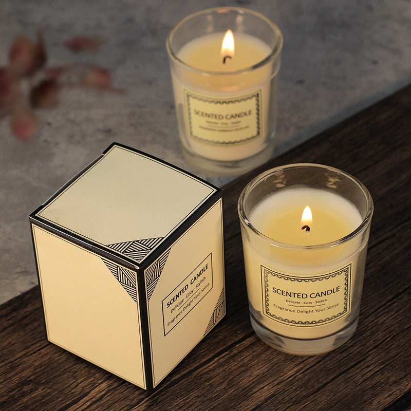 Two scented candles with their packaging on a wooden surface.