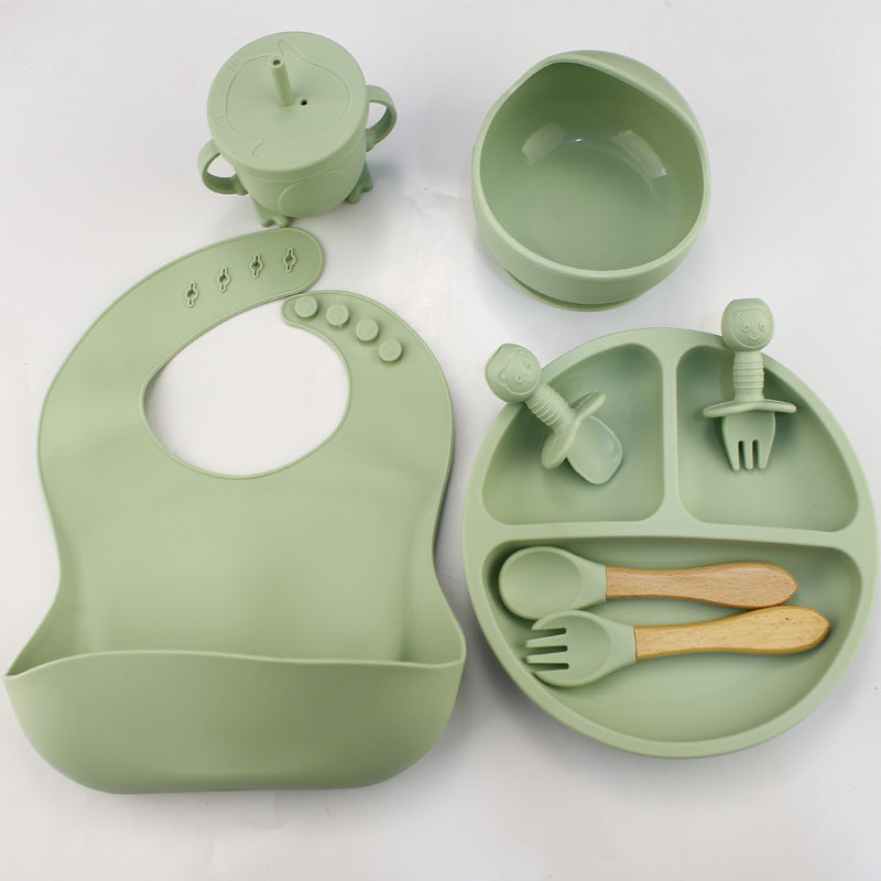 Green baby set including bib, cup, bowl, and utensils on a white background