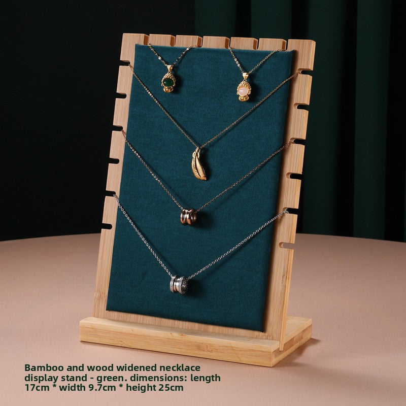 Three necklaces on a wooden display stand with a green fabric background