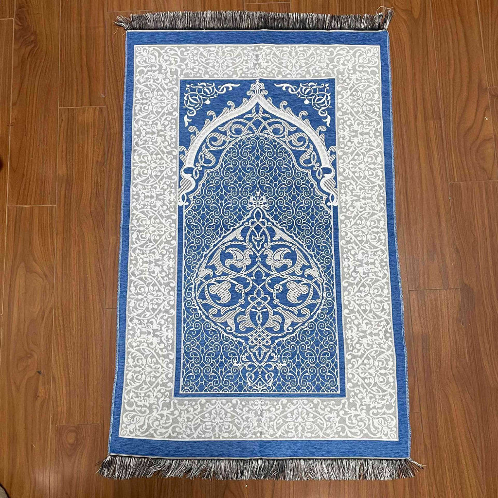 Decorative prayer mat with intricate blue and white design on a wooden floor.