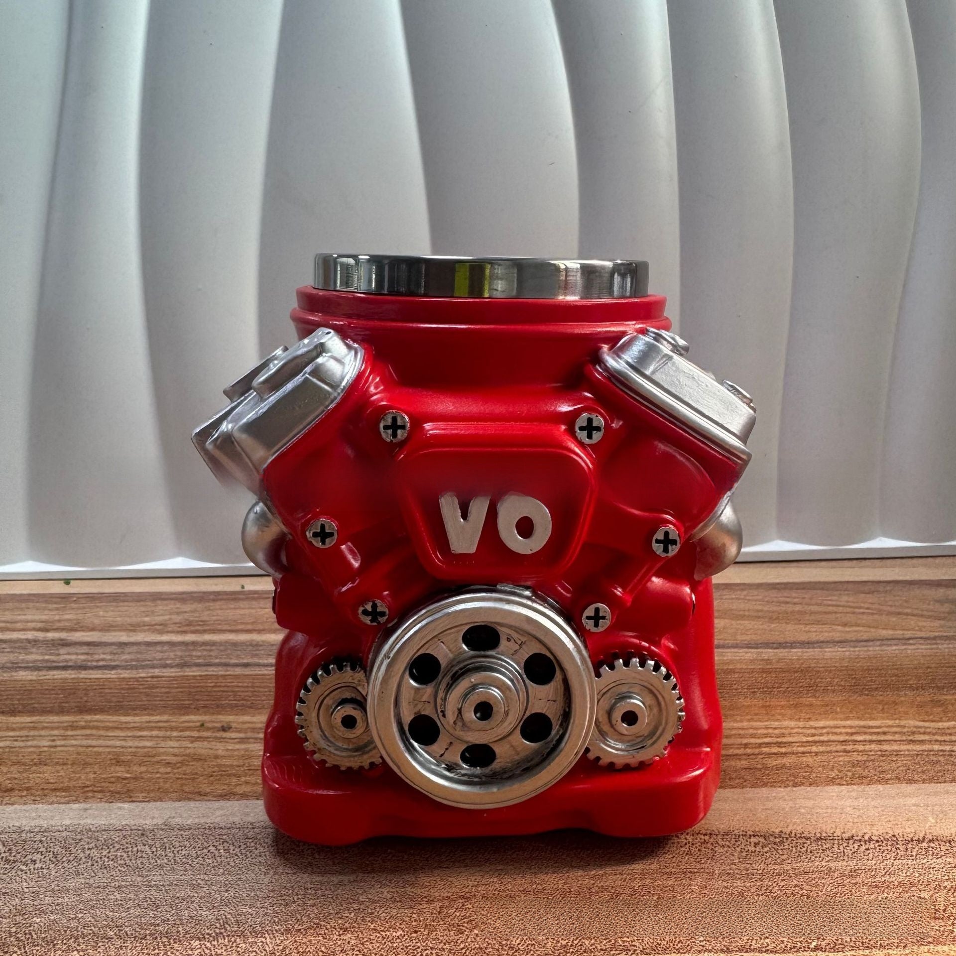 Red engine model with 'VO' branding on a wooden surface and white curtain background