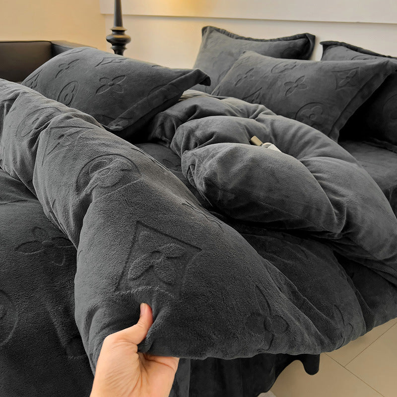 Gray textured comforter being held over a bed with matching pillows.