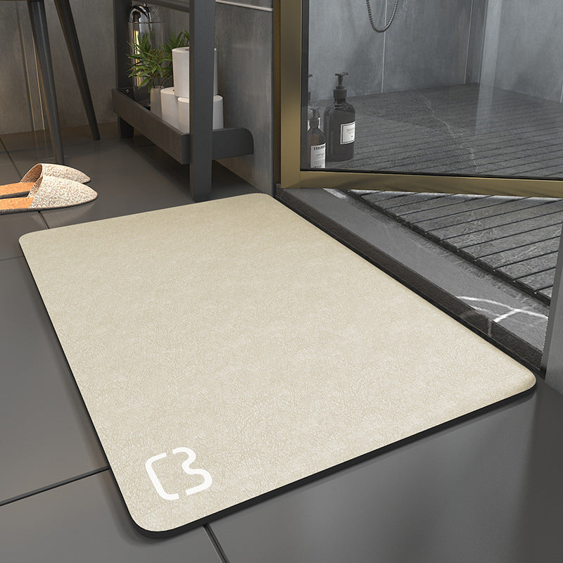 Beige doormat with a brand logo on a tiled floor next to a glass door.