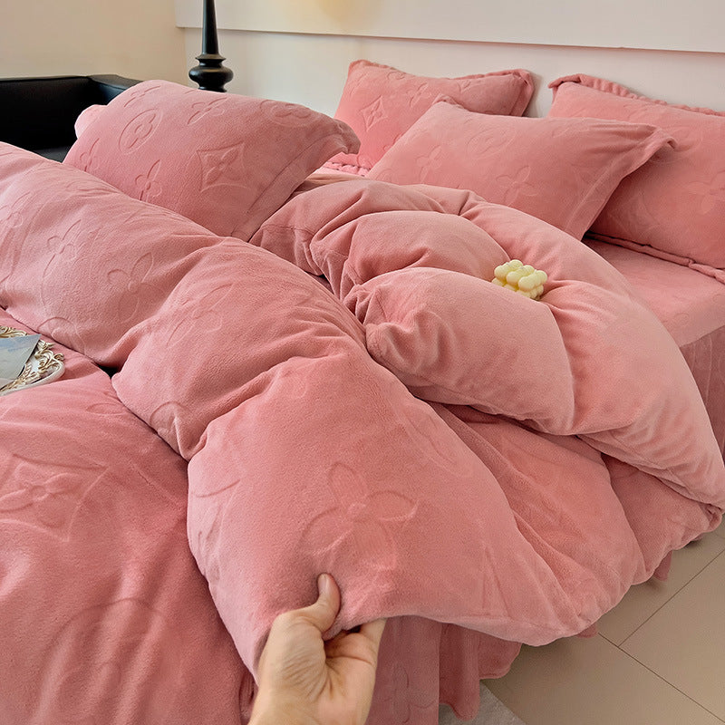 Pink textured comforter on a bed with a hand holding it