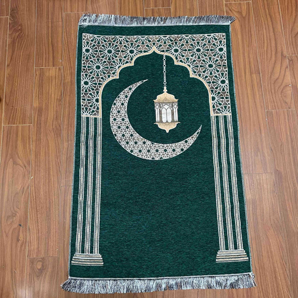 Green prayer mat with white crescent moon and lantern design on a wooden floor.