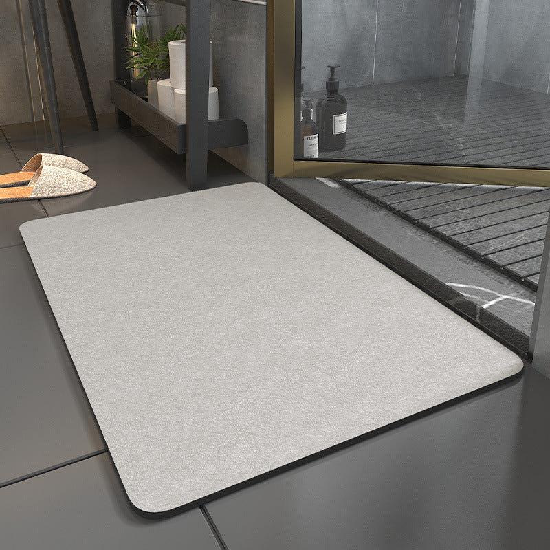 Gray bath mat on a tiled floor next to a shower area