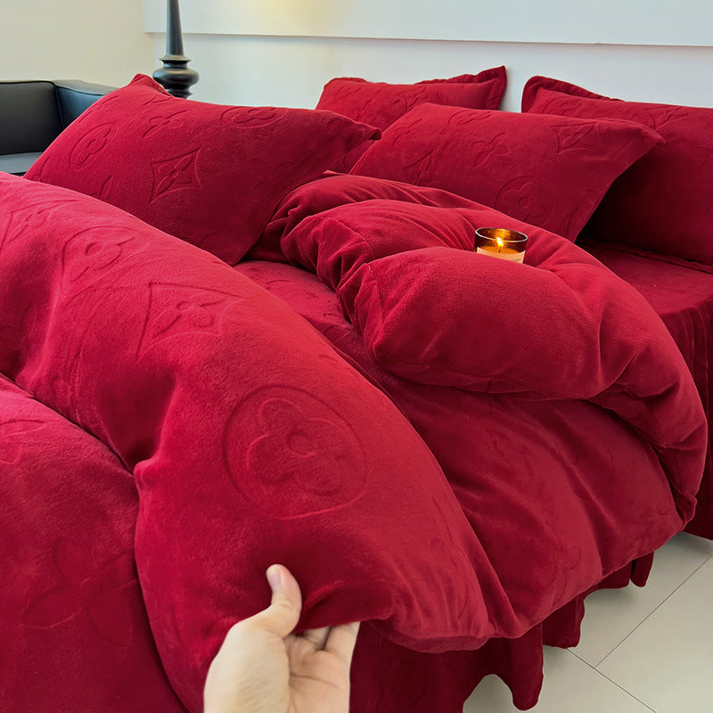 Red textured blanket and pillows on a sofa with a hand touching one of the pillows.