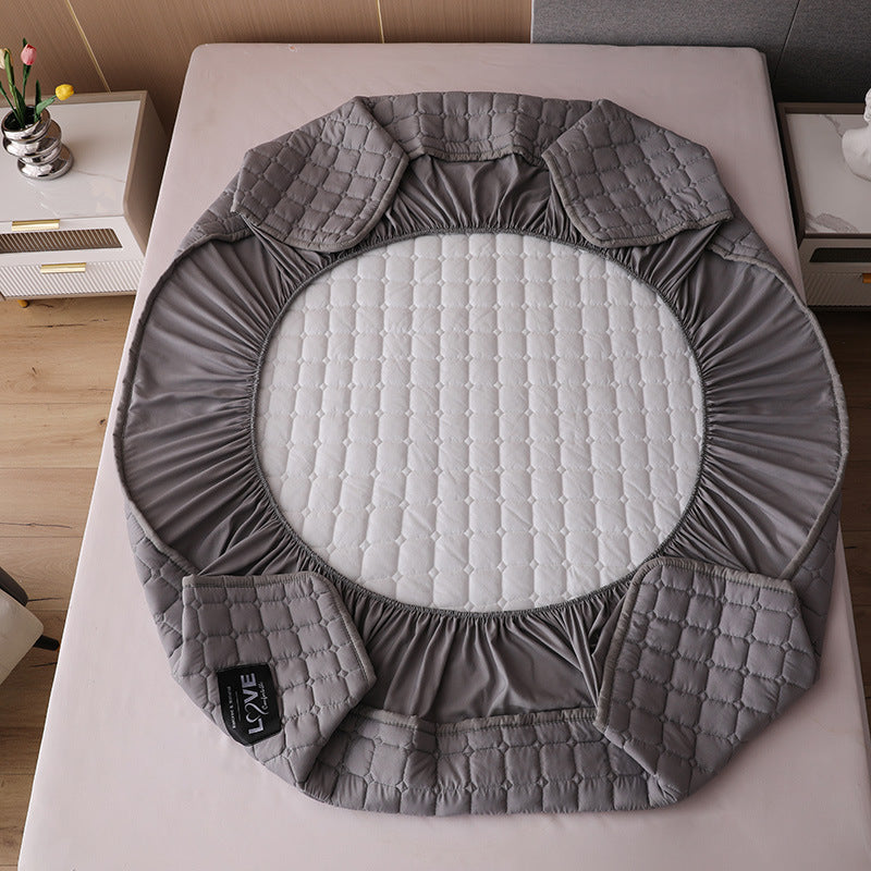 Gray quilted circular mat on a bed with a visible brand label.