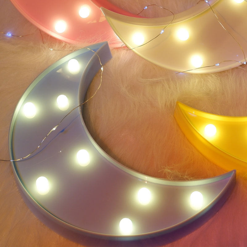 Decorative moon-shaped light fixture with string lights on a soft pink background