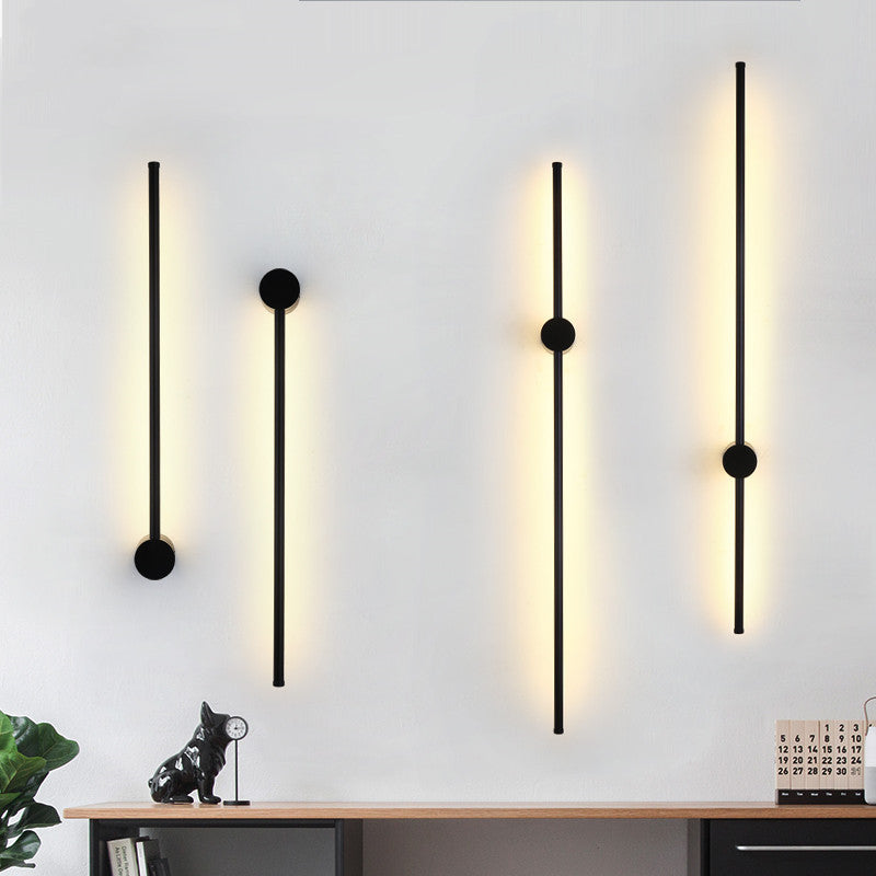 Two modern wall lights on a white wall with a desk and decor items below.