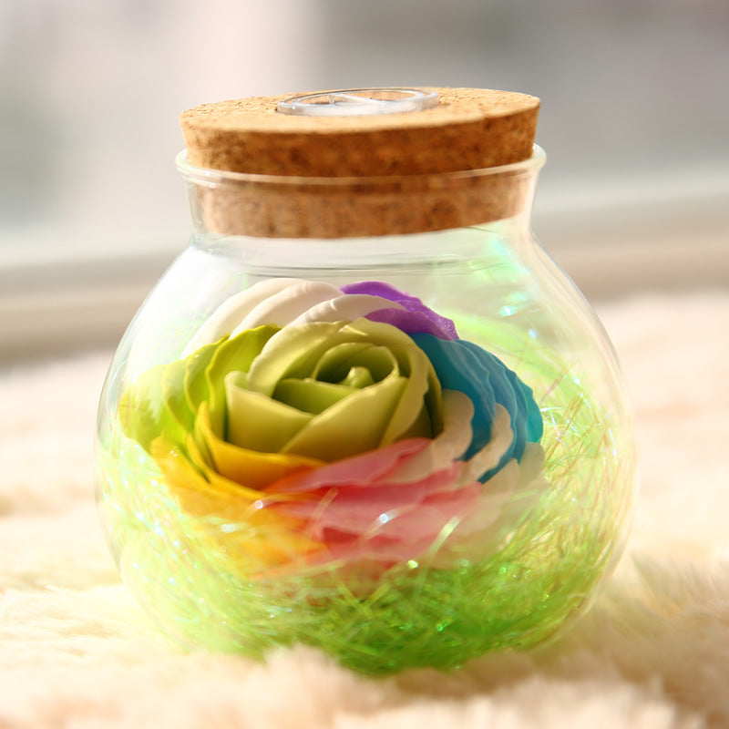 Glass jar with a wooden lid containing colorful rose-shaped bath bombs on a soft surface.