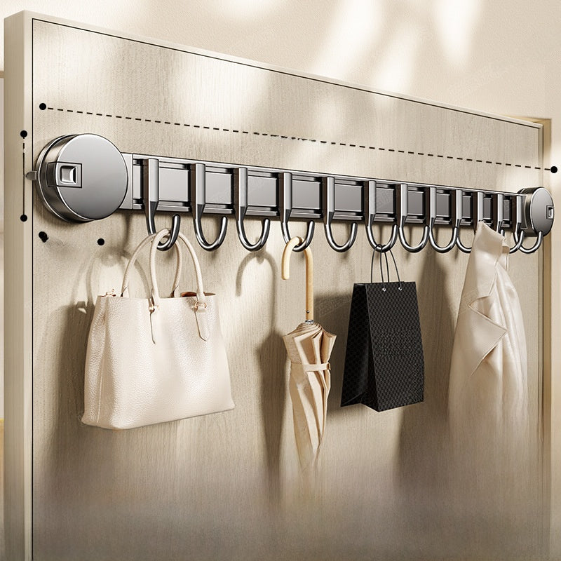 Wall-mounted hook rack with handbags, umbrella, and coat on a neutral background