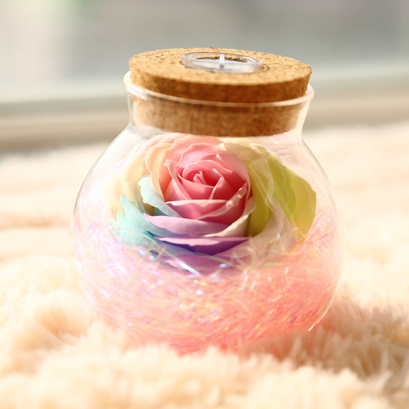 Glass jar with cork lid containing a colorful rose on a soft surface