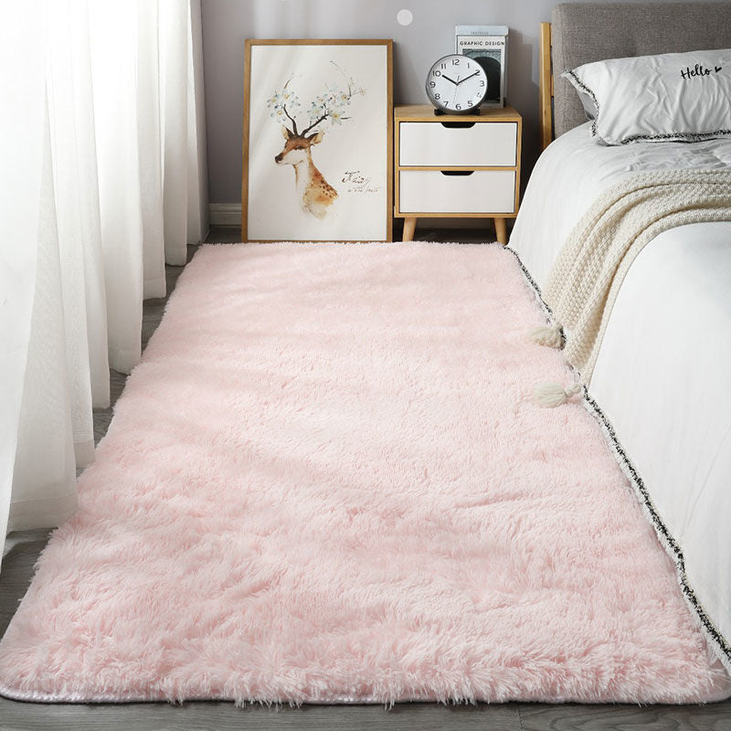 Pink rug in a bedroom with a bed, nightstand, and wall art.
