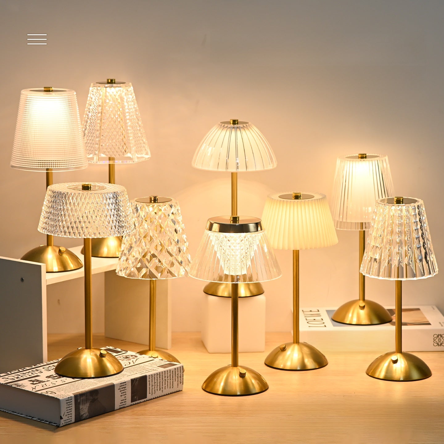 Set of gold table lamps with various lampshades on a wooden surface.