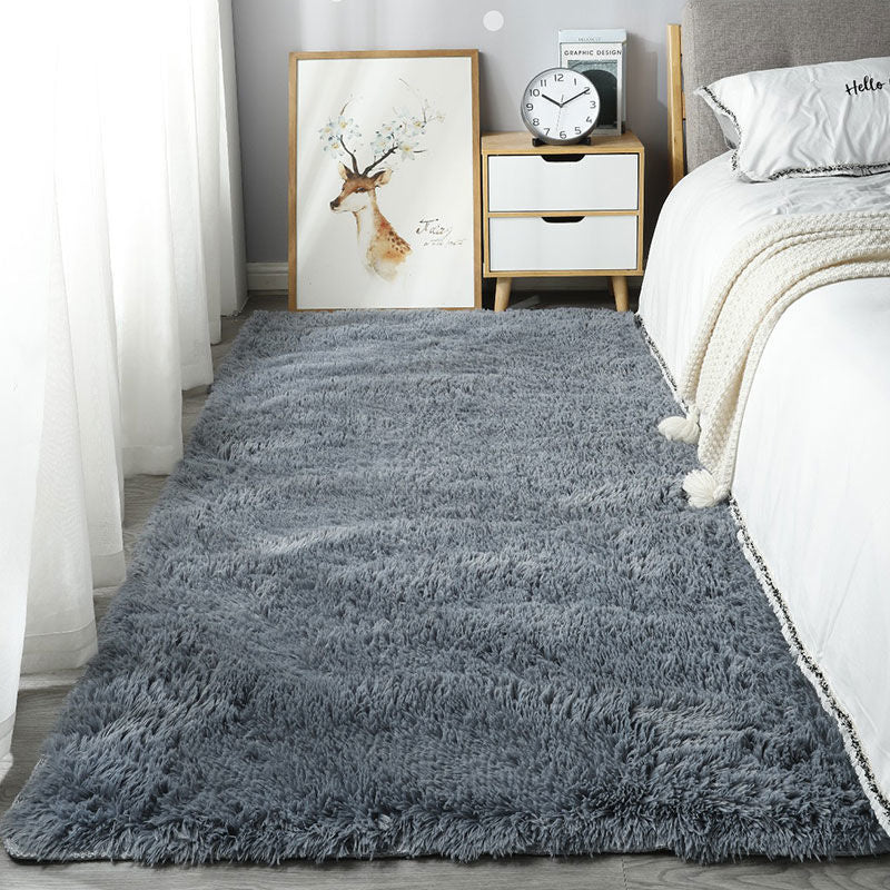 Gray shaggy rug in a bedroom setting with a bed, nightstand, and wall art.
