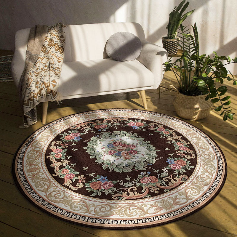 Round decorative rug with floral pattern on wooden floor in a room with a white sofa and plants.