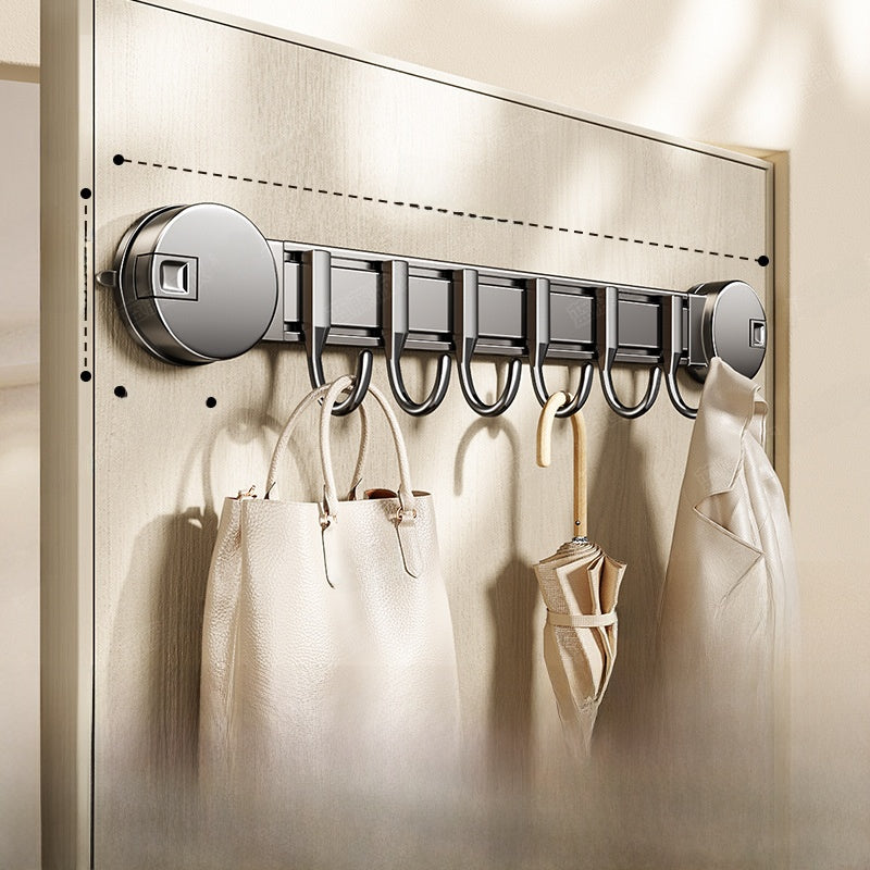 Wall-mounted hook rack with bags and coats hanging on a neutral wall.