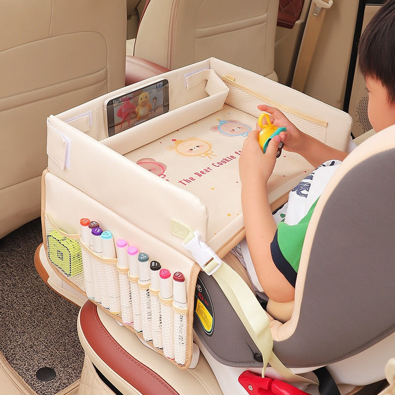Child sitting in a car seat with a portable playpen and art supplies.
