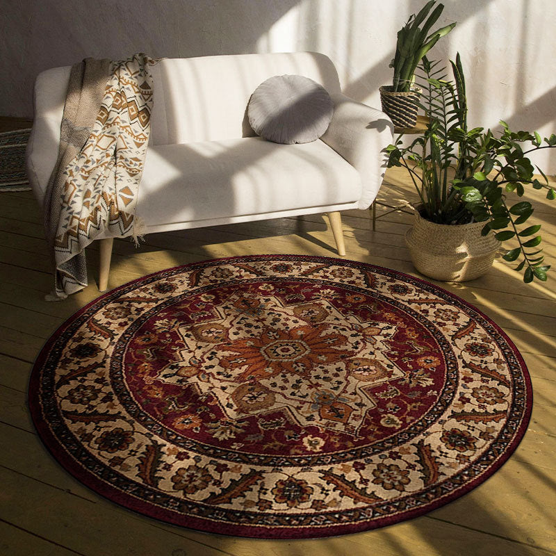 Round patterned rug in front of a white armchair with a plant in the background