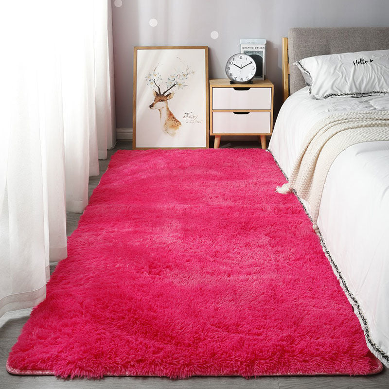 Hot pink rug in a bedroom setting with a bed and nightstand.
