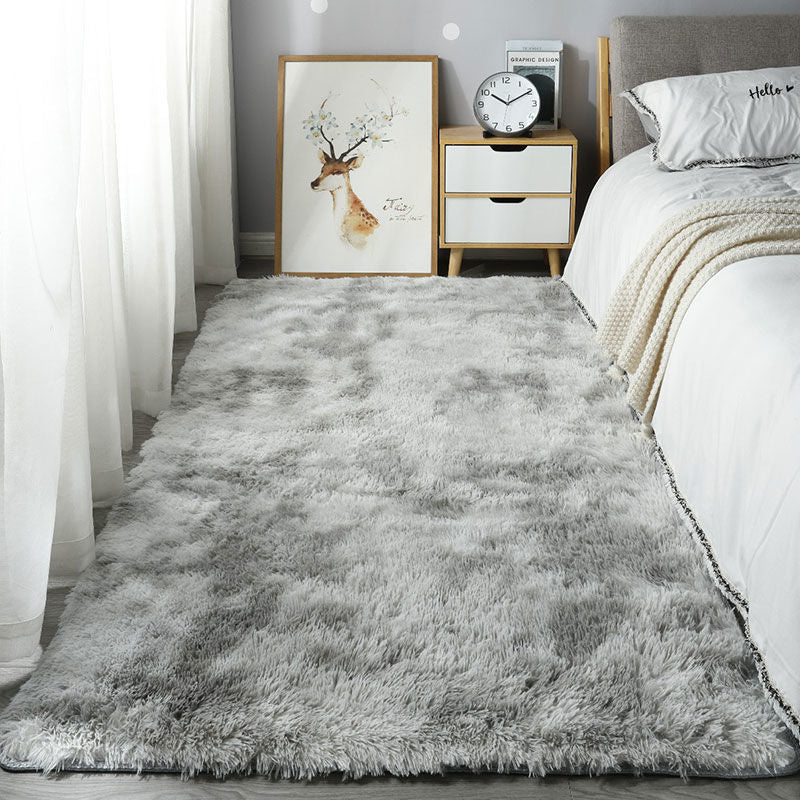 Gray shaggy rug in a bedroom setting with a bed, nightstand, and wall art.